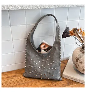 Grey studded shoulder bag detail shot, featuring metallic rivet design and hobo silhouette.