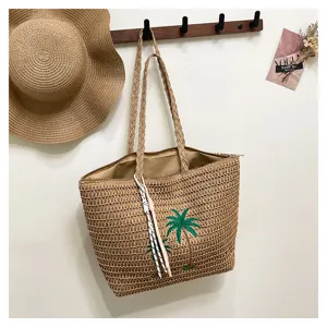 Woven straw tote bag detail, featuring embroidery palm tree pattern for a perfect summer holiday.