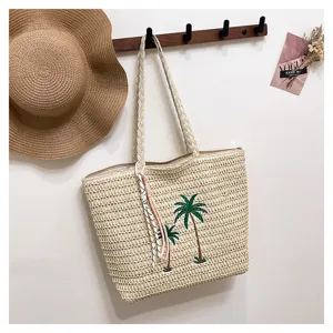 Detailed view of handmade woven straw beach tote bag with cute palm tree embroidery design.