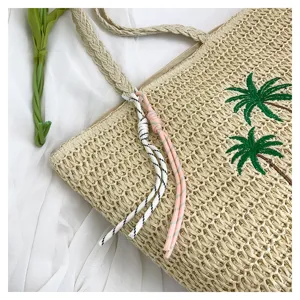 Handmade straw woven tote bag detail, summer beach shoulder bag with palm tree embroidery.