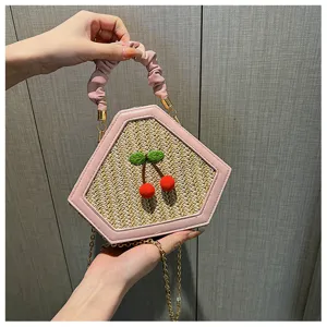 Pink straw woven crossbody bag detail showing cute cherry embroidery and chic pleated handle.