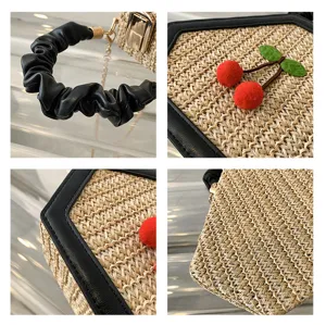 Detailed view of straw woven shoulder bag featuring black scrunchie handle and cute cherry decor.