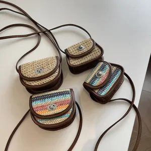 Mini straw crossbody bag detail showing multi-color woven pattern, leather trim and metal lock.