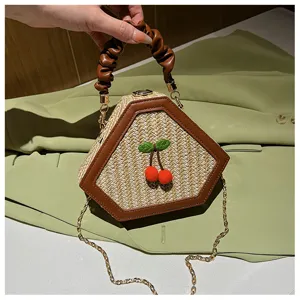 Chic hexagonal straw woven handbag with brown leather trim, cute cherry decor, and chain strap for women.