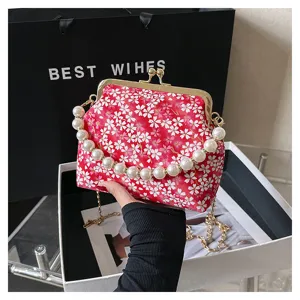 Red floral kiss-lock handbag with pearl handle and chain strap, vintage style evening bag detail.