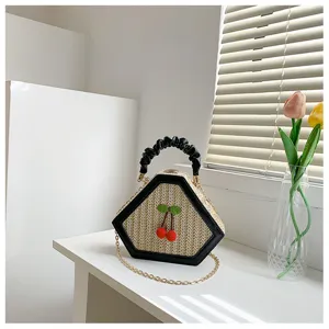 Chic straw woven handbag with cute cherry decor, rhombus shape, and stylish black handle.