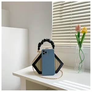 Detail view of the stylish diamond straw woven crossbody bag with black ruffled handle.