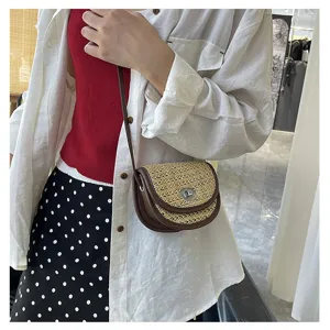 Mini straw woven crossbody bag with brown leather trim, detailed shot showing saddle design.