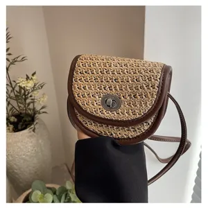 Straw woven saddle bag detail displaying contrast brown leather trim and metal turn-lock.
