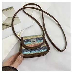 Detail view of the mini woven crossbody bag with colorful straw pattern and brown leather trim.