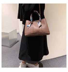 Gros plan du sac cabas en cuir marron avec foulard en soie coloré, look quotidien élégant.