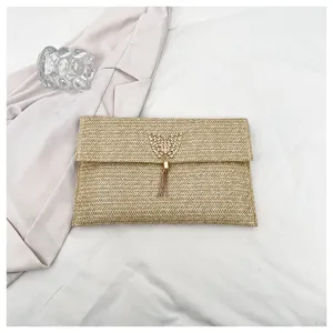 Primer plano detallado del bolso de mano de paja tejida con elegante mariposa y borla.