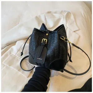 Detail shot of the black woven bucket bag showing metal buckle and textured straw design.