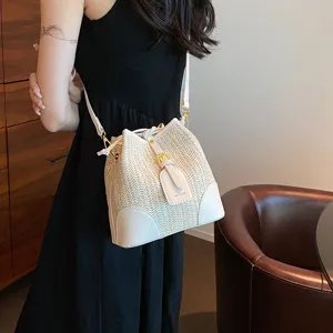 Woven bucket bag for women, summer straw shoulder handbag with drawstring and white leather trim.