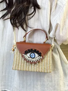 Summer woven straw handbag with cute eye bead embroidery, versatile crossbody beach bag.
