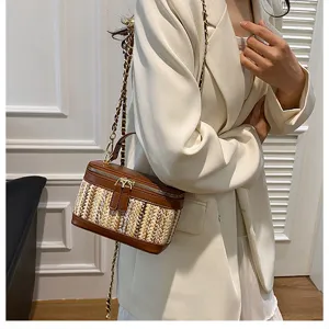 Chic straw woven vanity shoulder bag with brown leather trim and golden chain for women.