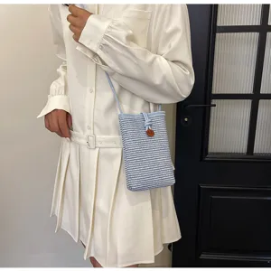 Woven crossbody phone bag detail, blue and white straw texture, drawstring closure design.