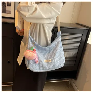 Detailed view of the light blue crinkled shoulder bag featuring a cute plush charm and strap.