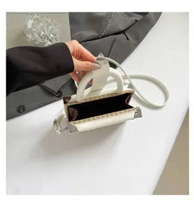Vue détaillée du sac bandoulière boîte tissé élégant avec un design bicolore et sa lanière.