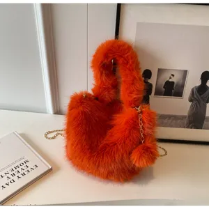 Close-up detail of stylish orange plush handbag with gold chain strap in aesthetic scene.