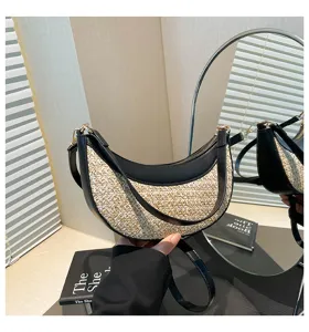 Close-up detail of stylish straw crescent shoulder bag with black PU leather trim and hardware.