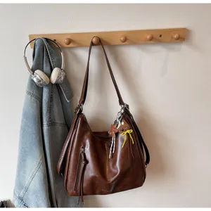Vue détaillée du sac cabas en cuir marron suspendu au mur avec un joli petit pendentif.