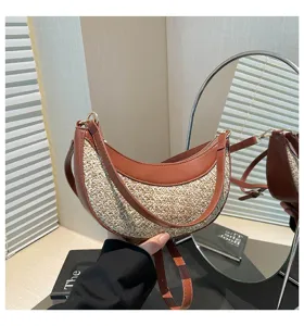 Close-up detail of the stylish crescent straw shoulder bag with brown leather trim in interior view.