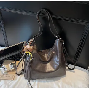 Vue détaillée du sac à épaule rétro en cuir marron avec charm ours et poches pratiques.