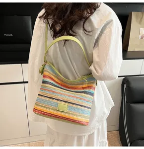 Detailed view of a women's colorful striped woven straw shoulder bucket bag with green handles.