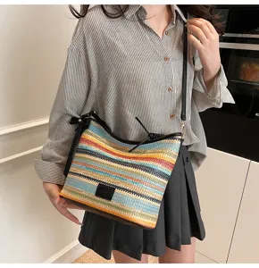 Detailed shot of colorful woven shoulder bag, stylish striped bucket bag design with black strap.
