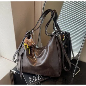 Vue détaillée du sac porté épaule rétro marron avec joli charm ours et design à lanières.