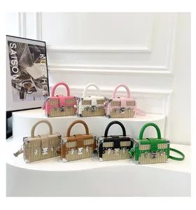 Sac à bandoulière carré en paille tressée tendance avec bordure en cuir et coins métalliques.