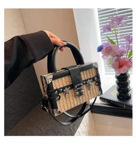 Vue détaillée du sac boîte élégant en paille tissée avec bordure en cuir PU et coins en métal.