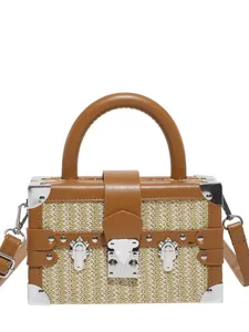 Sac à bandoulière boîte en paille tissée avec similicuir, coins métalliques et poignée.