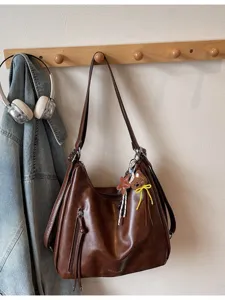 Sac à dos bandoulière hobo en cuir marron vintage accroché au mur vue principale