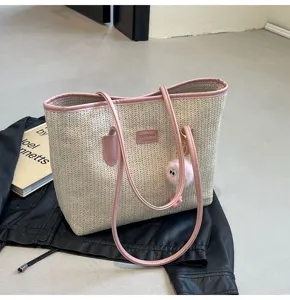 Straw tote bag detail view, casual commuter handbag with pink PU leather trim and fuzzy charm.