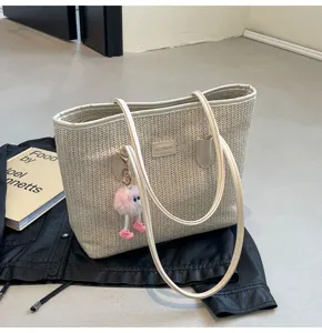 Detail view of stylish woven straw tote bag with leather straps and cute plush charm.