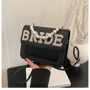 Borsa a tracolla in paglia intrecciata nera con lettera BRIDE in perle e manico elegante.