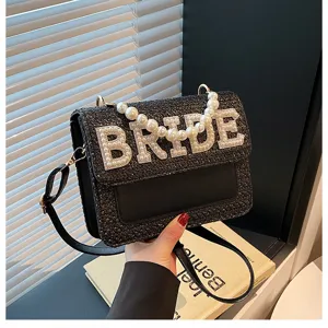 Borsa a tracolla intrecciata nera decorata con lettere BRIDE in perle e manico chic di perle.