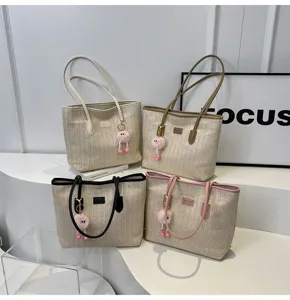 Detailed view of large capacity straw tote bag with color block handles and cute furry charm.