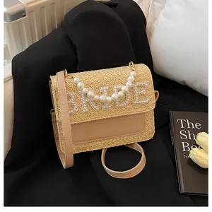 Primo piano dettagliato della borsa a tracolla in paglia da sposa con perle BRIDE.