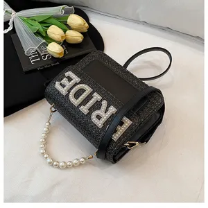 Vista dettagliata della borsa da sposa in paglia intrecciata nera con manico di perle.