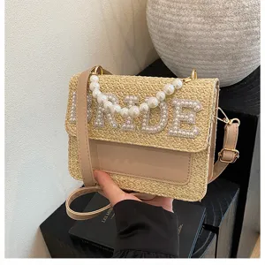 Dettaglio borsa tracolla in paglia lettera BRIDE perla con trama intrecciata e manico perle.