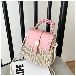 Detailed view of the stylish woven straw box bag with pink flap, handle and rope strap.