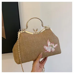 Chic straw woven handbag with golden kiss-lock frame, chain strap and elegant flower embroidery.