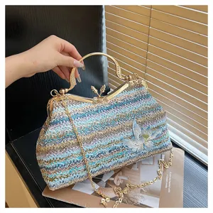 Detailed view of colorful woven handbag with metal handle, kiss-lock clasp and floral embroidery.