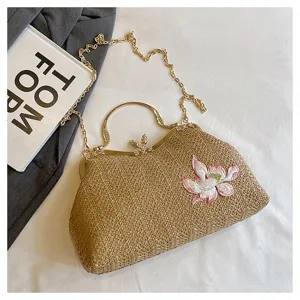 Chic straw woven handbag with golden metal frame, top handle and chain strap for summer style.