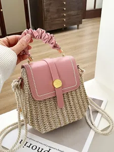Stylish woven straw crossbody box bag with pink leather flap, top handle and rope strap.