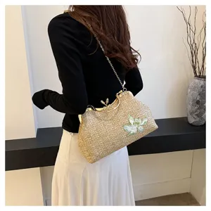Straw woven shoulder bag detail view, featuring elegant floral embroidery and chic gold chain strap.