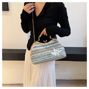 Detailed shot of casual woven straw handbag with colorful stripes, metal chain and floral embroidery.